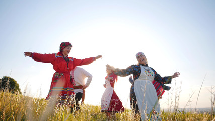 Wall Mural - Happy people in traditional russian clothes performing a round dance on the field