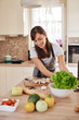 © nenadaksic - Beautiful hardworking housewife taking salad from bowl while standing in kitchen. Home made dinner preparation concept.