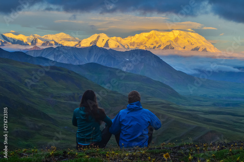Fotomural Sunrise view of Mount Denali - mt Mckinley peak with alpenglow during golden hour with two persons from Stony Dome overlook