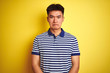 © Krakenimages.com - Young asian chinese man wearing striped polo standing over isolated yellow background depressed and worry for distress, crying angry and afraid. Sad expression.