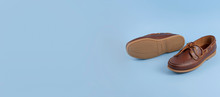 Brown mens topsiders shoes on blue background with reflection. Fashion advertising shoes. Copy space