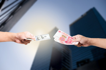 One hand hold dollar banknote and another hand hold Yuan banknote on skyscraper for exchange and trade war concept. -Isolated image.