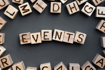 Fototapete - the word events wooden cubes with burnt letters, celebration, gray background top view, scattered cubes around random letters
