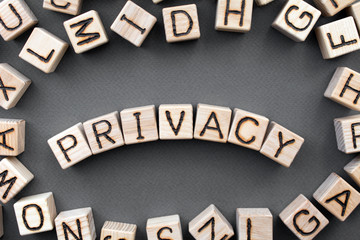 Fototapete - the word privacy wooden cubes with burnt letters, data confidentiality, gray background top view, scattered cubes around random letters