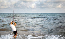 Fisherman Standing At The Seashore Hooks A Fish.