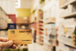 © sommart - Hand holding credit card with blur supermarket, shopping and retail concept