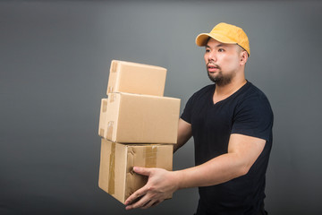 Smiling handsome asian delivery man wearing cap, giving and carrying parcel, cardboard box, Moving house day and express delivery concept