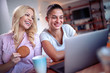 Two beautiful young women at home using laptop