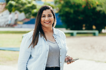 portrait of beautiful plus size woman using her smartphone outdoors