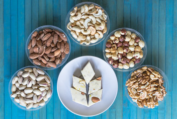 Wall Mural -  Oriental dessert halva with pistachio, almond, cashew nuts, peanut, walnut  on a  plate. Image. Healthy food. Nuts mix assortment. sweets, Turkish Delight. Isolated  background.. Eastern delicacy