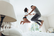 Couple Jumping On Bed