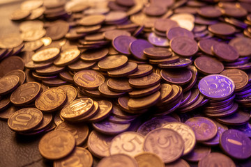 a handful of gold and silver coins in a violet light. a handful of coins of rubles in dark light.