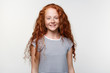 © timtimphoto - Portrait of positive cute freckles little girl with ginger hair, stands over white wall and broadly smiling, looks happy and glad.