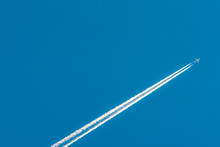 Airplane With White Condensation Tracks. Jet Plane On Clear Blue Sky With Vapor Trail. Travel By Aeroplane Concept. Trails Of Exhaust Gas From Airplane Engine. Aircraft With White Stripes.