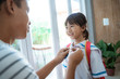 © Odua Images - happy kid wearing school uniform her father help her to button the shirt on