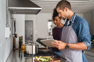 Couple cooking togheter with digital tablet