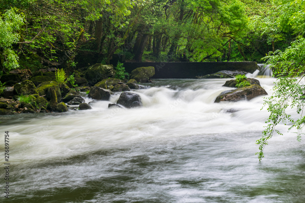 río con aguas rápidas y rocas por medio tras sobrepasar pequeña represa ...
