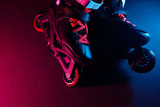 Close up view of roller skates inline skate or rollerblading on dark grunge background in neon blue magenta pink light