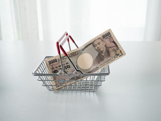 Japanese Yen in shopping basket on white background