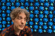 Portrait Of A Forty Something Man Wearing An Asian Themed Shirt In Front Of A Cool, Unusual Background Of Blue Swirly Flowers.