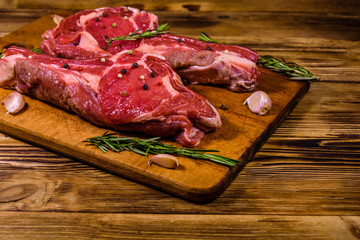 Raw ribeye steak, spices, rosemary and garlic on cutting board