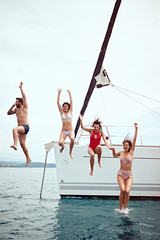 Wall Mural - vacation, travel, sea, friendship and people concept - Friends jumping from sailing boat in sea..