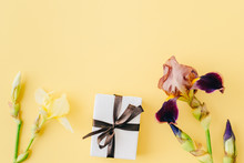 Flat Lay Composition With Yellow, Brown Irises And Gift Box On A Yellow Background