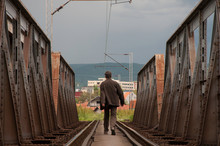Man Walking On A Rail Bridge