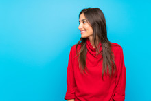 Young Woman With Red Sweater Over Isolated Blue Background Looking To The Side