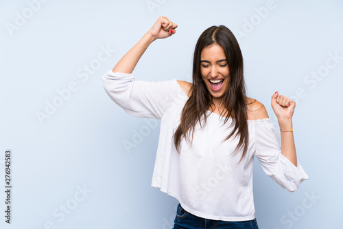 Cuadros en Lienzo Young woman over isolated blue background celebrating a victory