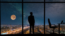 The Man Standing Near The Panoramic Window On City With Starry Sky Background