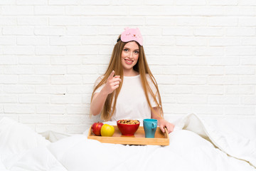 Young woman in dressing gown with breakfast points finger at you