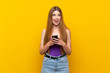 © luismolinero - Young woman over isolated yellow background surprised and sending a message