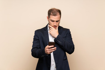 Blonde man over isolated background thinking and sending a message