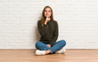 © luismolinero - Young woman sitting on the floor showing a sign of silence gesture putting finger in mouth