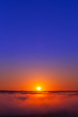 golden-blue summer sunrise over fog without clouds in minimalistic composition