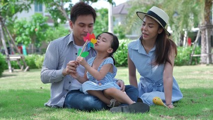 Wall Mural - Happy Asian family. Father, mother and daughter, Thailand three people in a park at natural sunlight background. Family warmth, vacation concept. Slow Motion