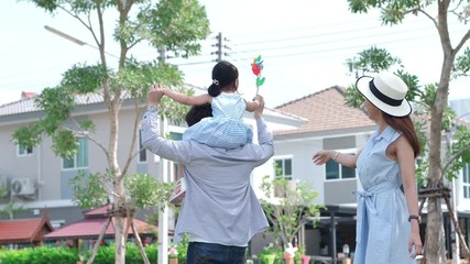 Wall Mural - Happy Asian family. Father gave his daughter to ride a neck in the garden in home page at natural sunlight background. Family warmth, vacation concept. Slow Motion