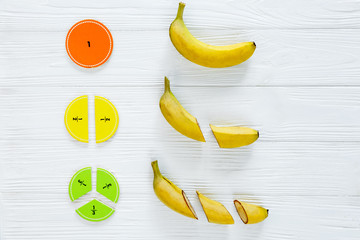 сolorful math fractions and bananas as a sample on white wooden background or table. interesting mat