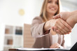 Business partners shaking hands at table after meeting, closeup. Space for text