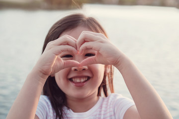 Happy Asian girHappy Asian girl making a heart shape with her hands for heart health and giving donation concept