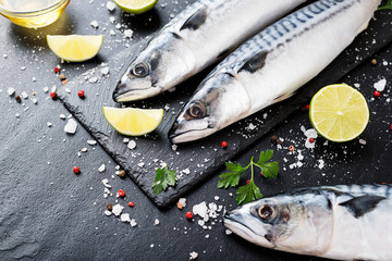 Wall Mural - Fresh fish. Mackerel with salt, lemon and spices on black stone background. 