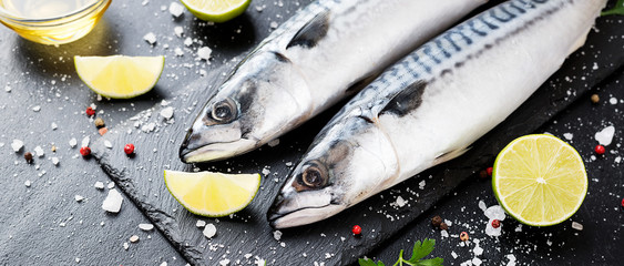 Wall Mural - Fresh fish. Mackerel with salt, lemon and spices on black stone background. 