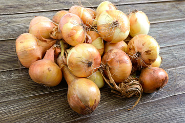 Wall Mural - A large bunch of onions on a wooden table. Fresh harvest, popular healthy vegetables.