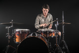 Fototapeta  - Professional drummer playing on drum set on stage on the black background