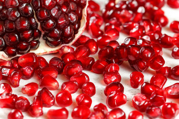 Wall Mural - Close up photo - bright red gem like pomegranate seeds with one halved fruit in background