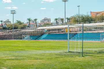 common football stadium sport complex building concept photography with gates foreground green grass field and empty tribunes background 