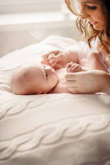 A young mother cares for and plays with a newborn baby.