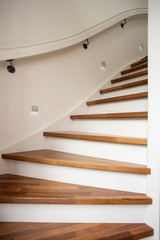 Modern steel staircase with wooden steps in a new apartment in a residential building with spots light in wall