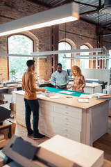 Wall Mural - Men and woman standing near the table in publishing office